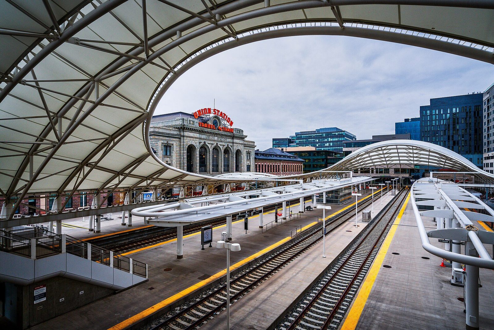 The white canopy of Denver Union Station's train hall with the 1914 station building behind it