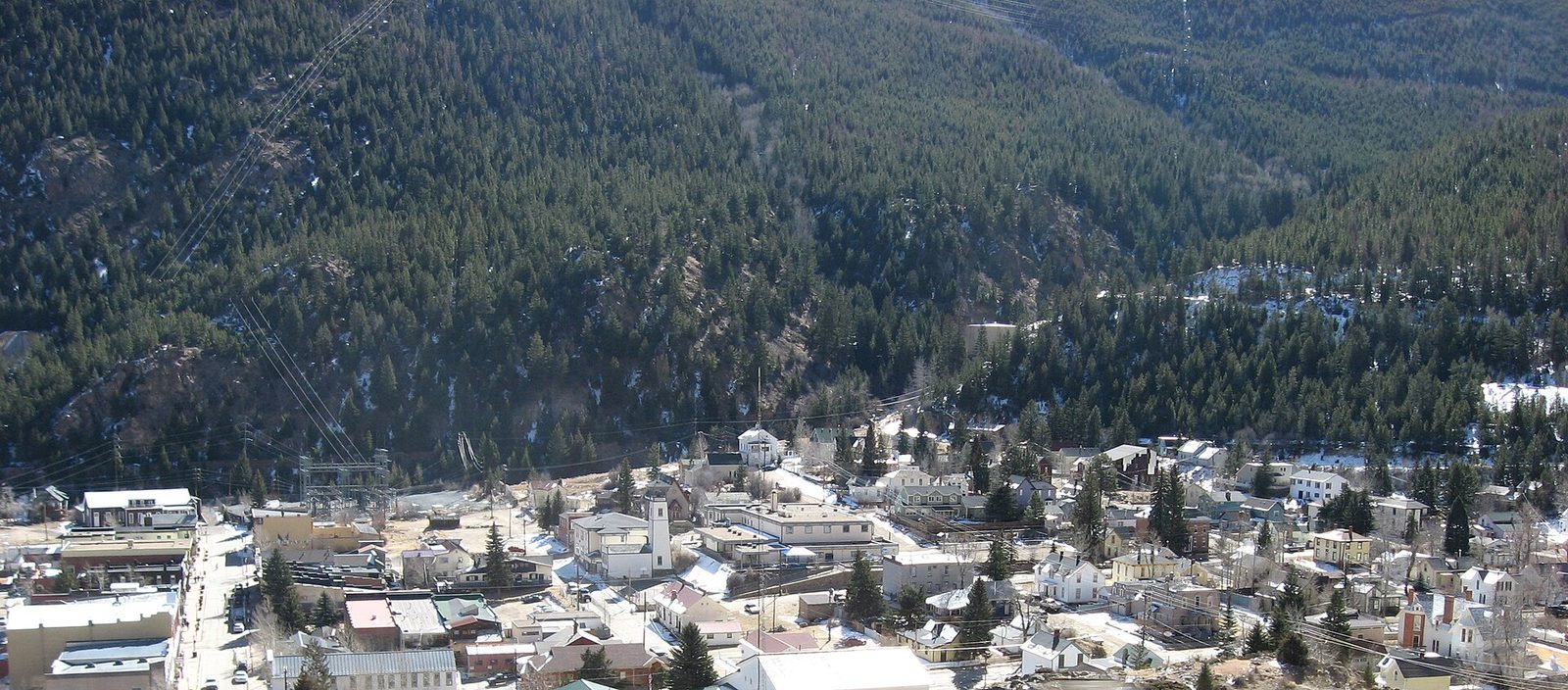 The historic town of Georgetown, Colorado seen from above in winter, its grid of Victorian buildings filling a narrow forested valley